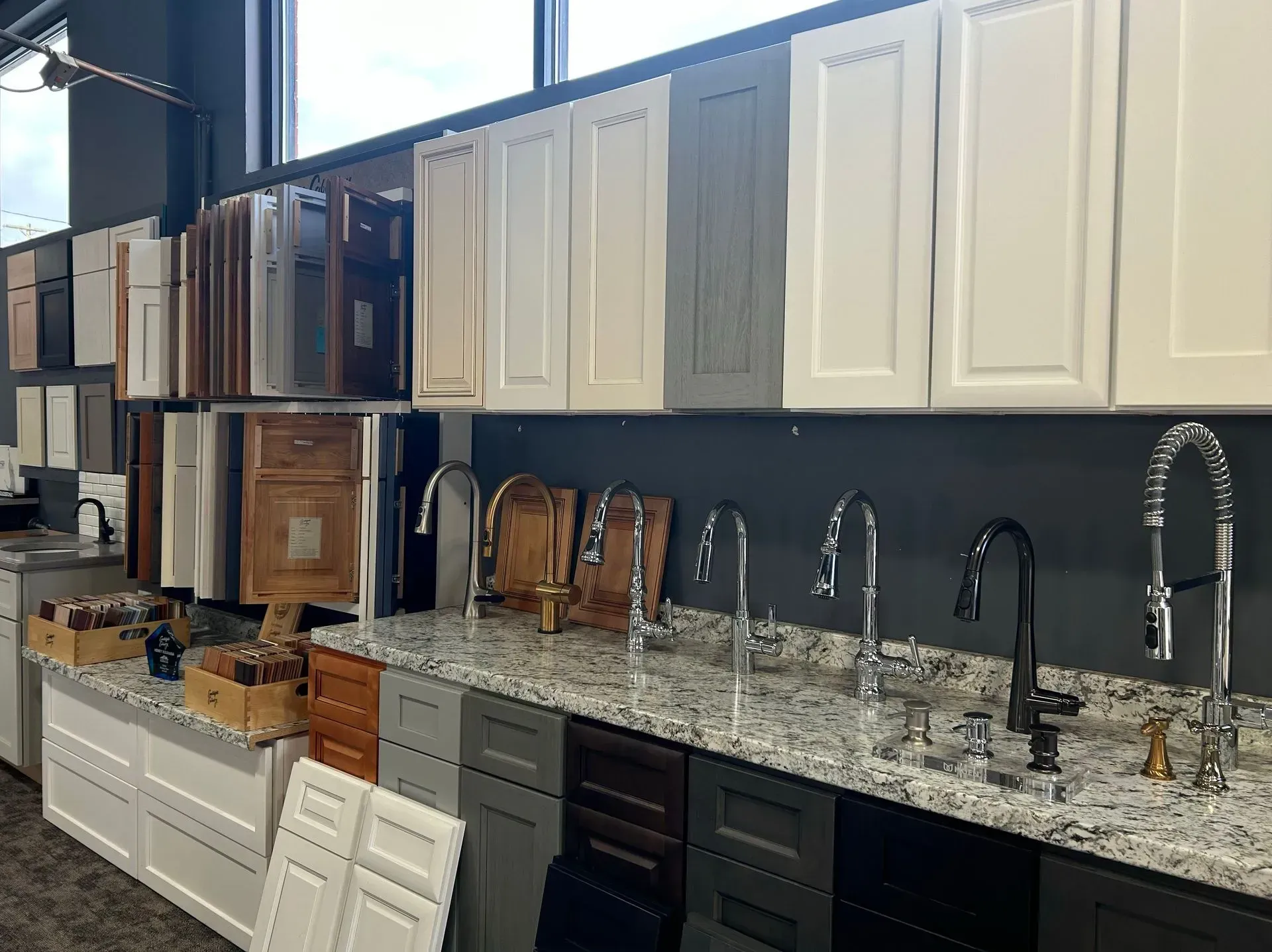A kitchen with a lot of cabinets and faucets on the counter.