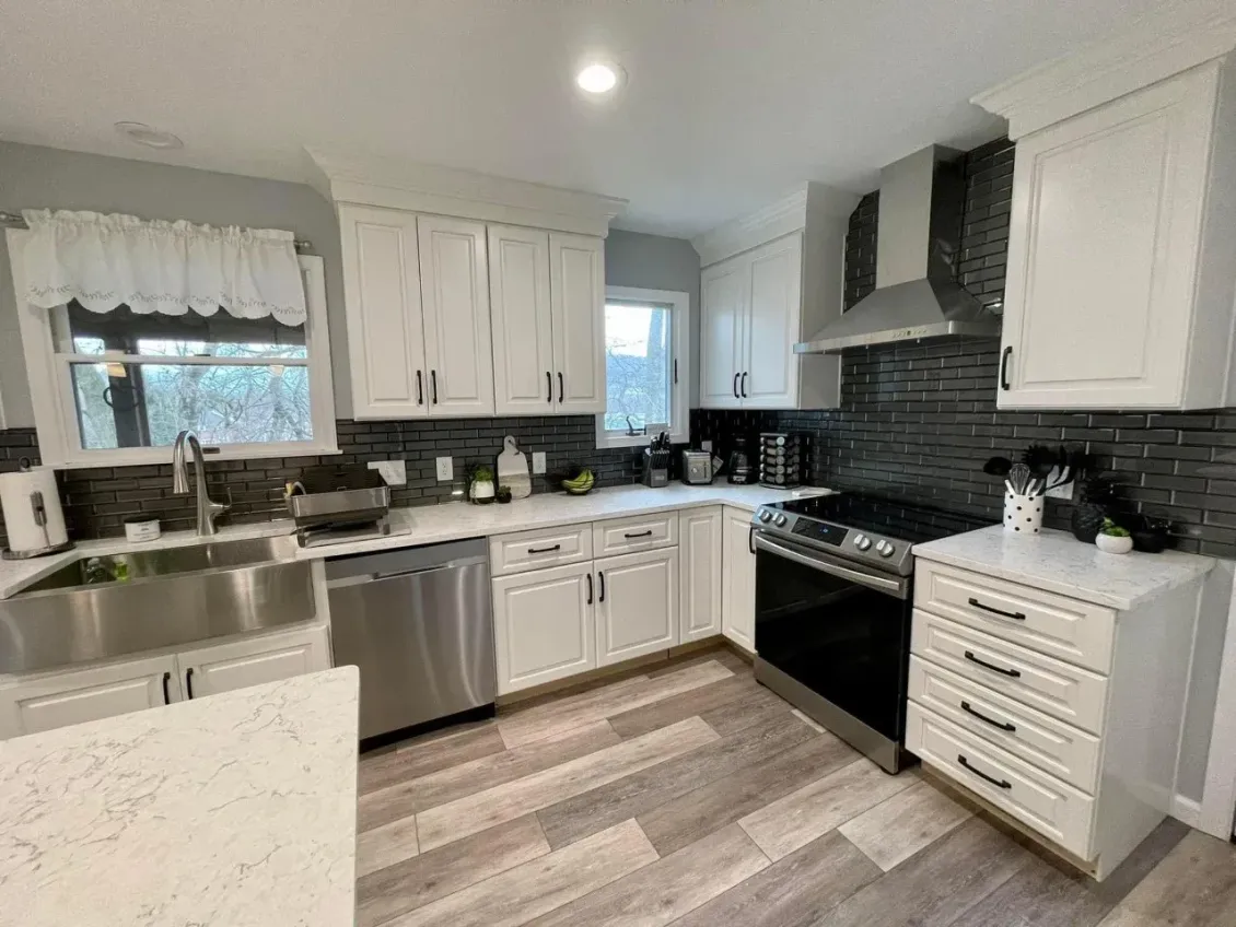 A kitchen with white cabinets , stainless steel appliances , a sink , and a stove.