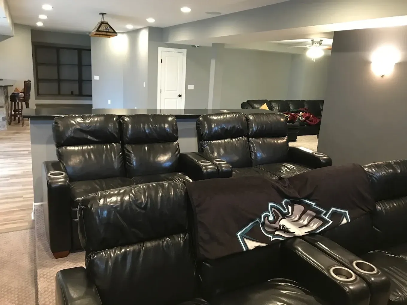A living room with a couch and chairs and a blanket on the couch