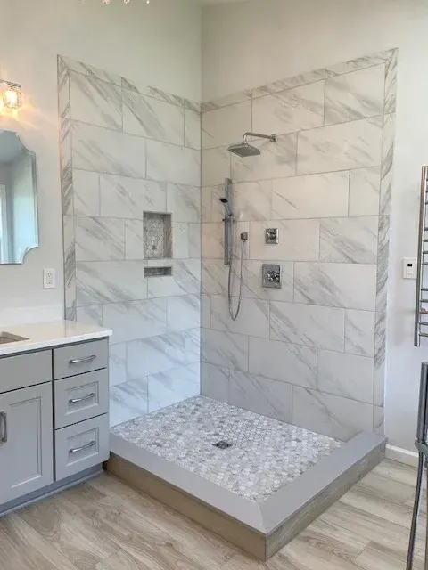 A bathroom with a walk in shower and a sink.