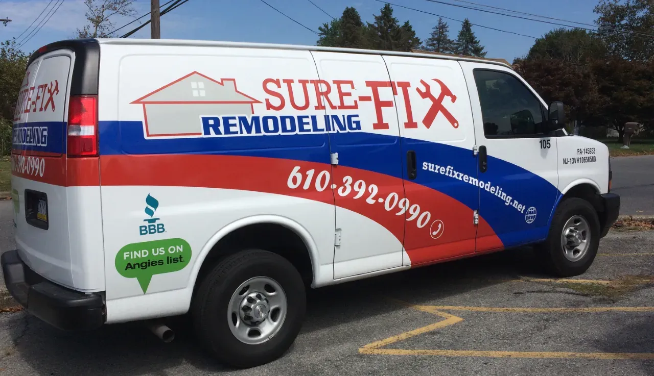 A sure-fix remodeling van is parked in a parking lot