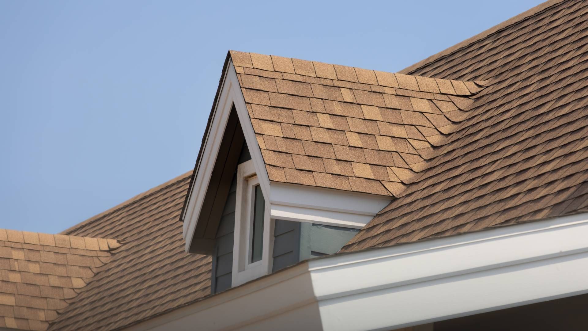 A roof with a window on it and a blue sky in the background.