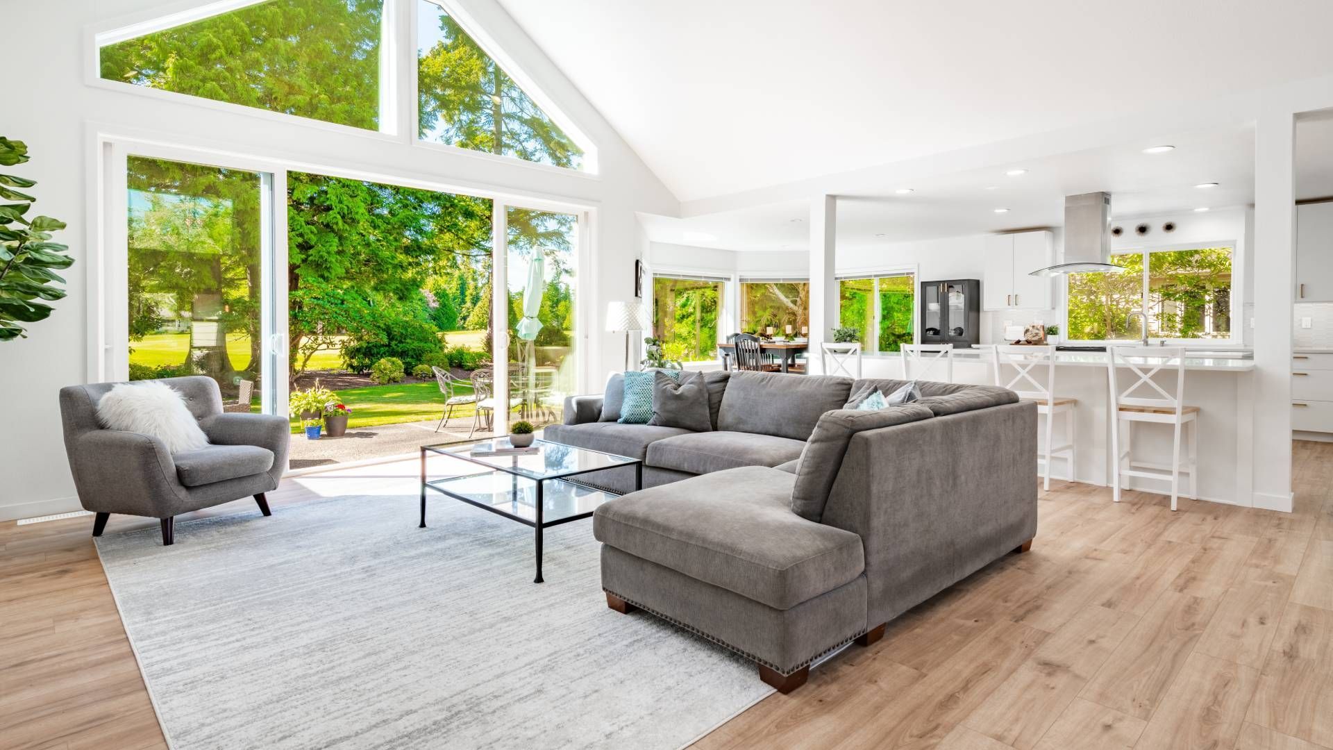 A living room with a couch , chairs , coffee table and large windows.