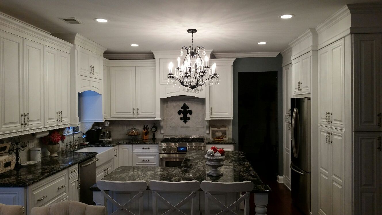 A kitchen with white cabinets and a chandelier hanging from the ceiling.