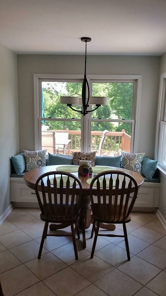 A dining room with a table and chairs and a window seat.