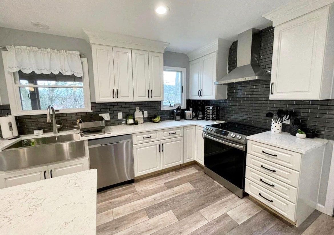 A kitchen with white cabinets , stainless steel appliances , a sink , and a stove.