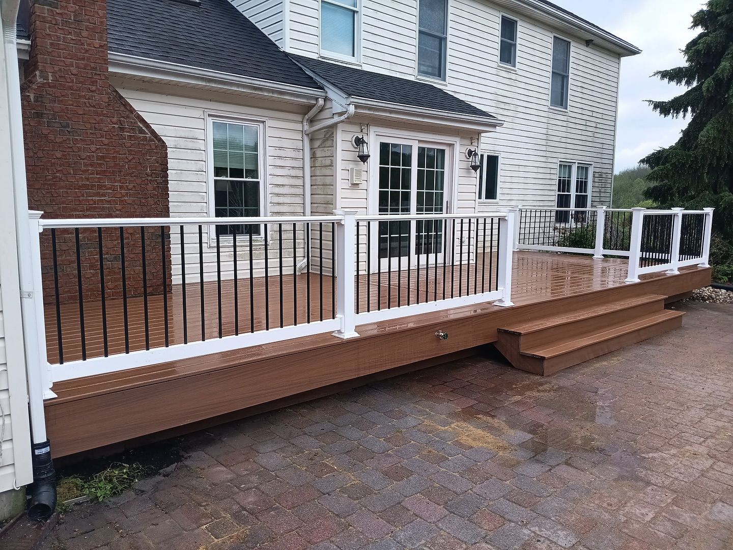A large white house with a wooden deck and stairs in front of it.