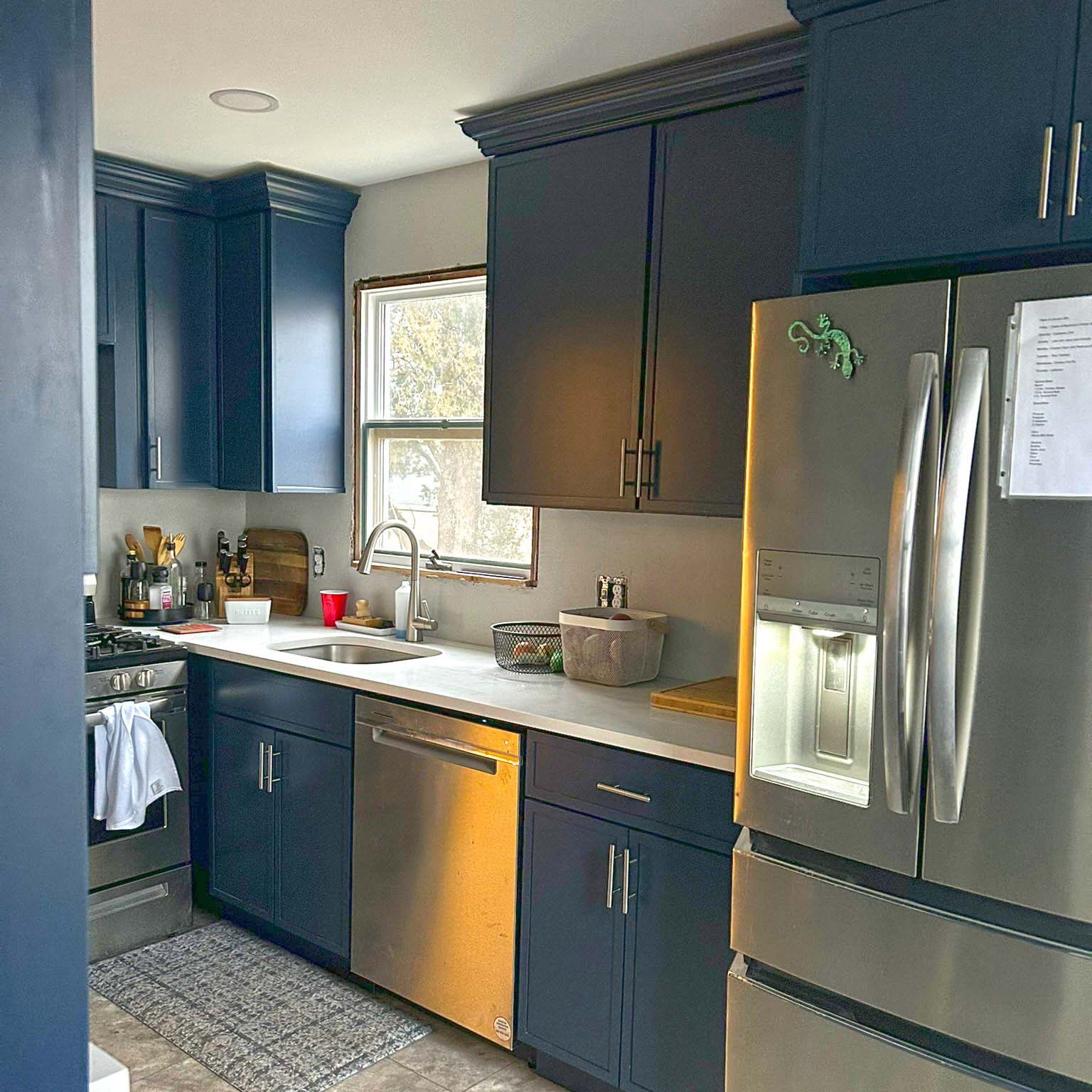 A kitchen with blue cabinets and a stainless steel refrigerator
