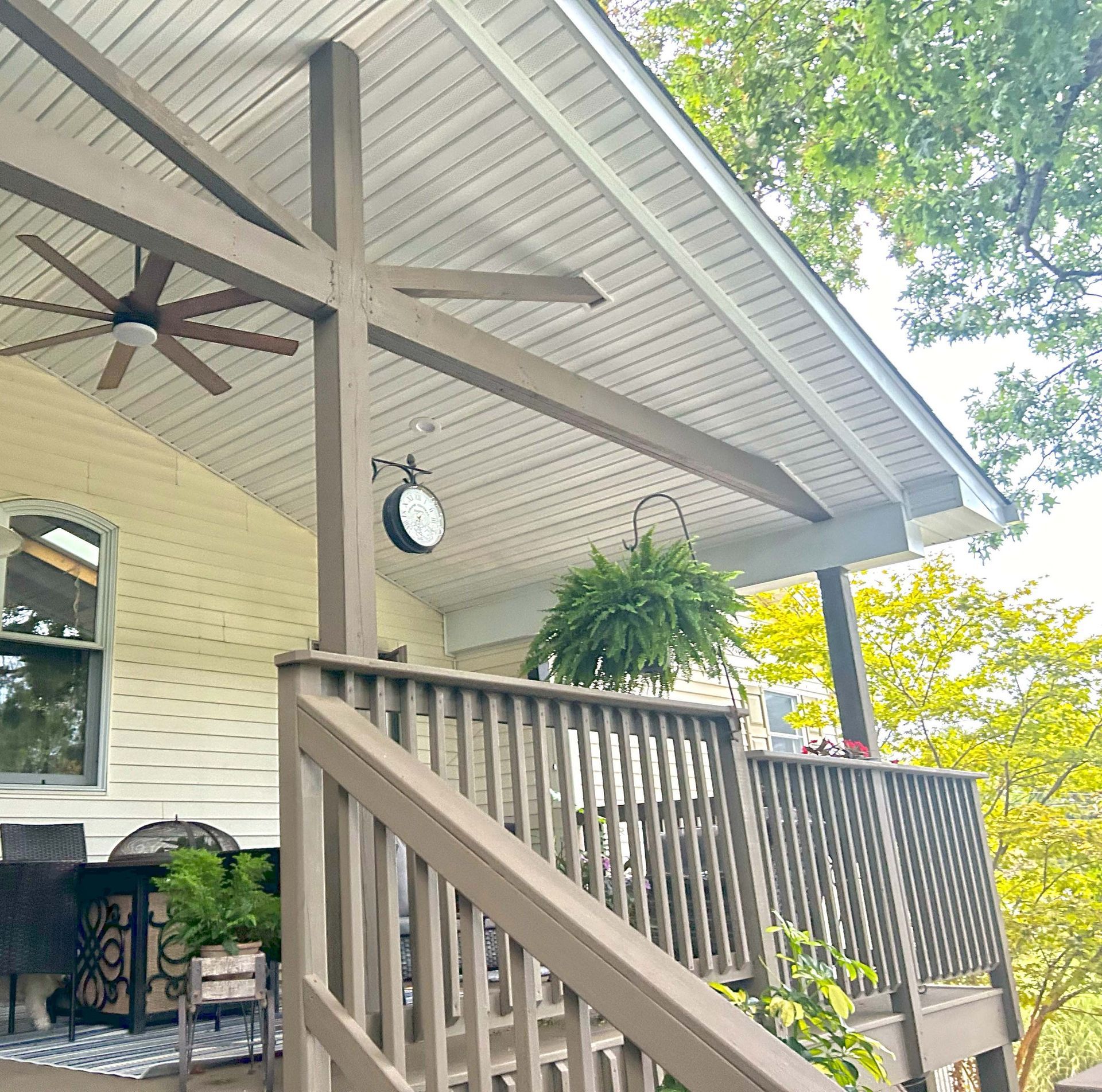 A porch with a clock on it and a ceiling fan