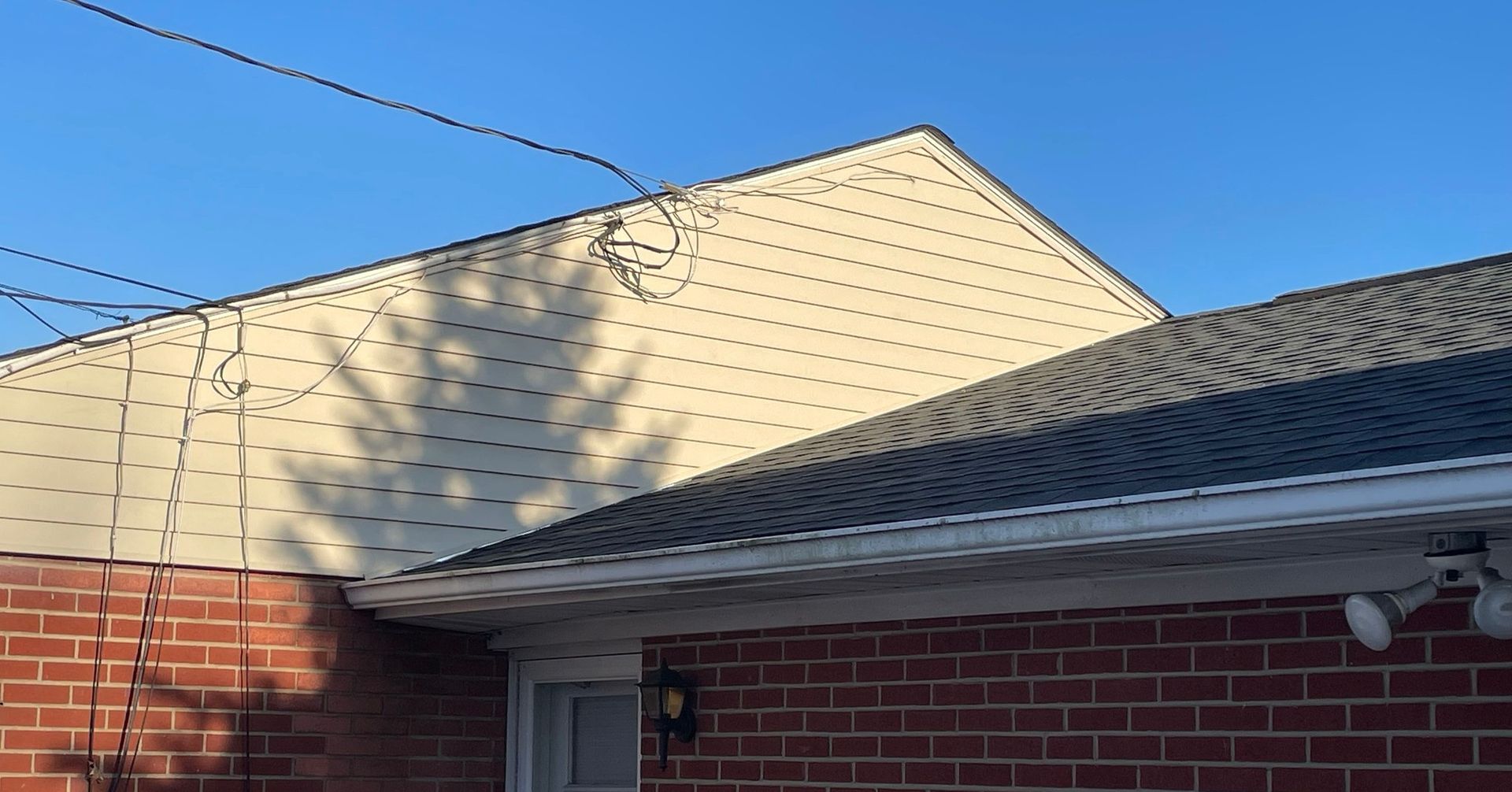 A brick house with a white siding and a black roof.
