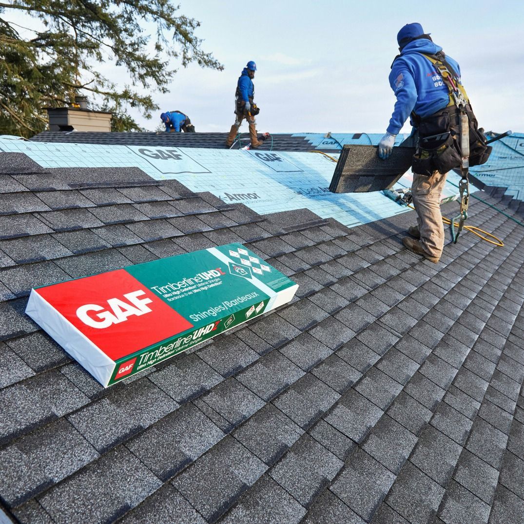 A man is laying shingles on a roof next to a book that says gaf.