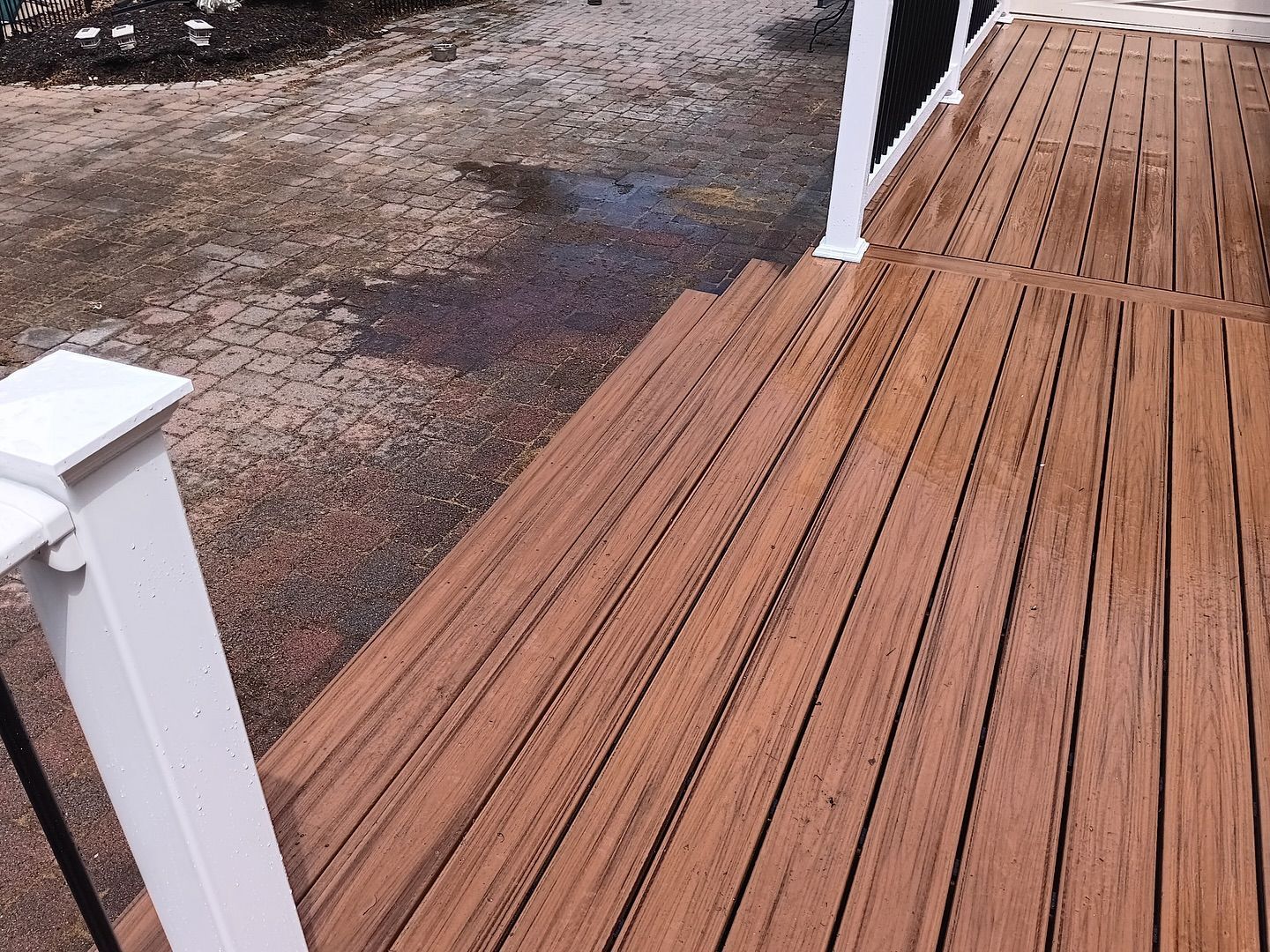 A wooden deck with a white railing and stairs leading up to it.