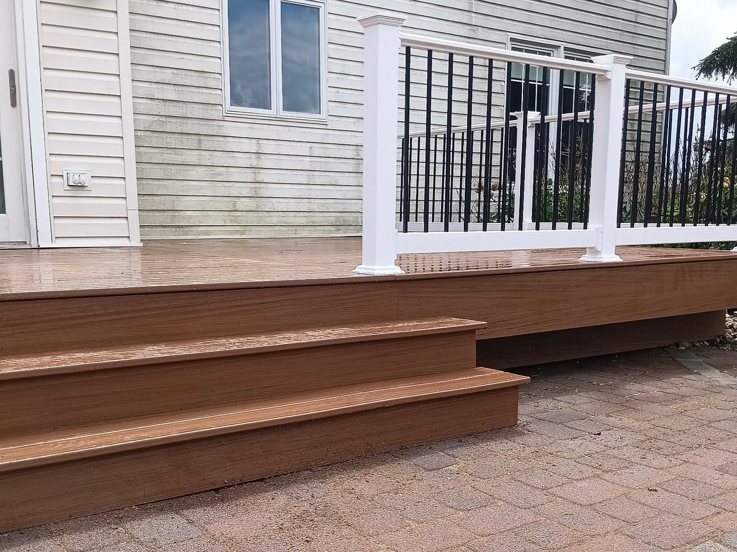 A wooden deck with stairs and a white railing in front of a house.