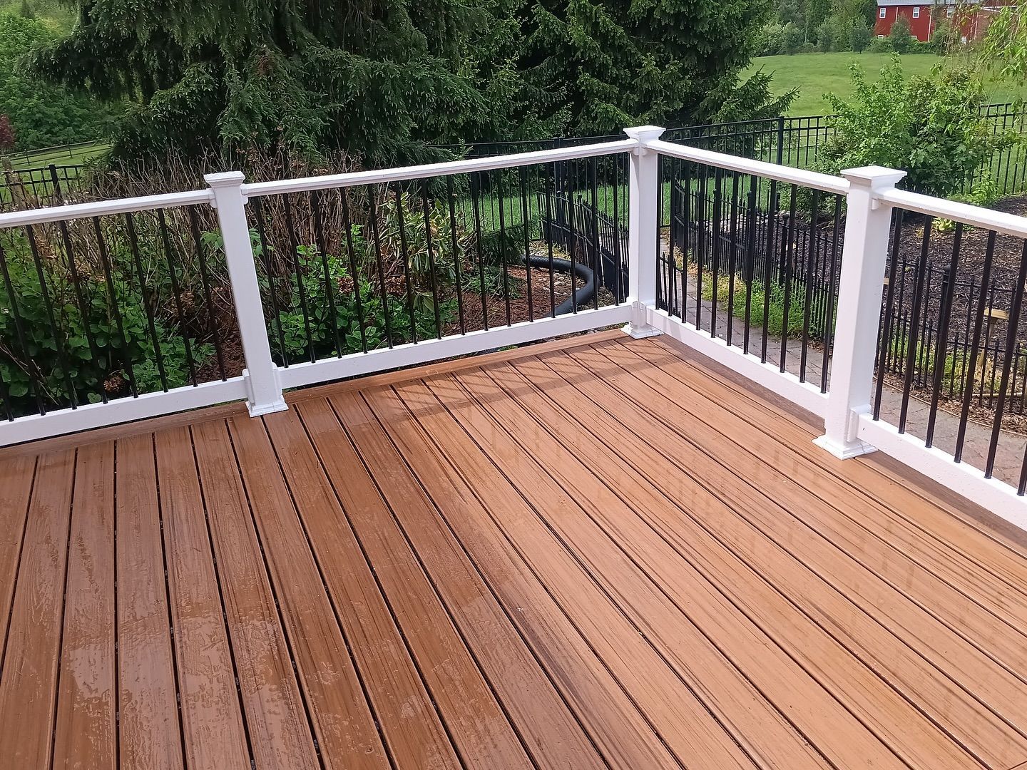 A wooden deck with a white railing and trees in the background.