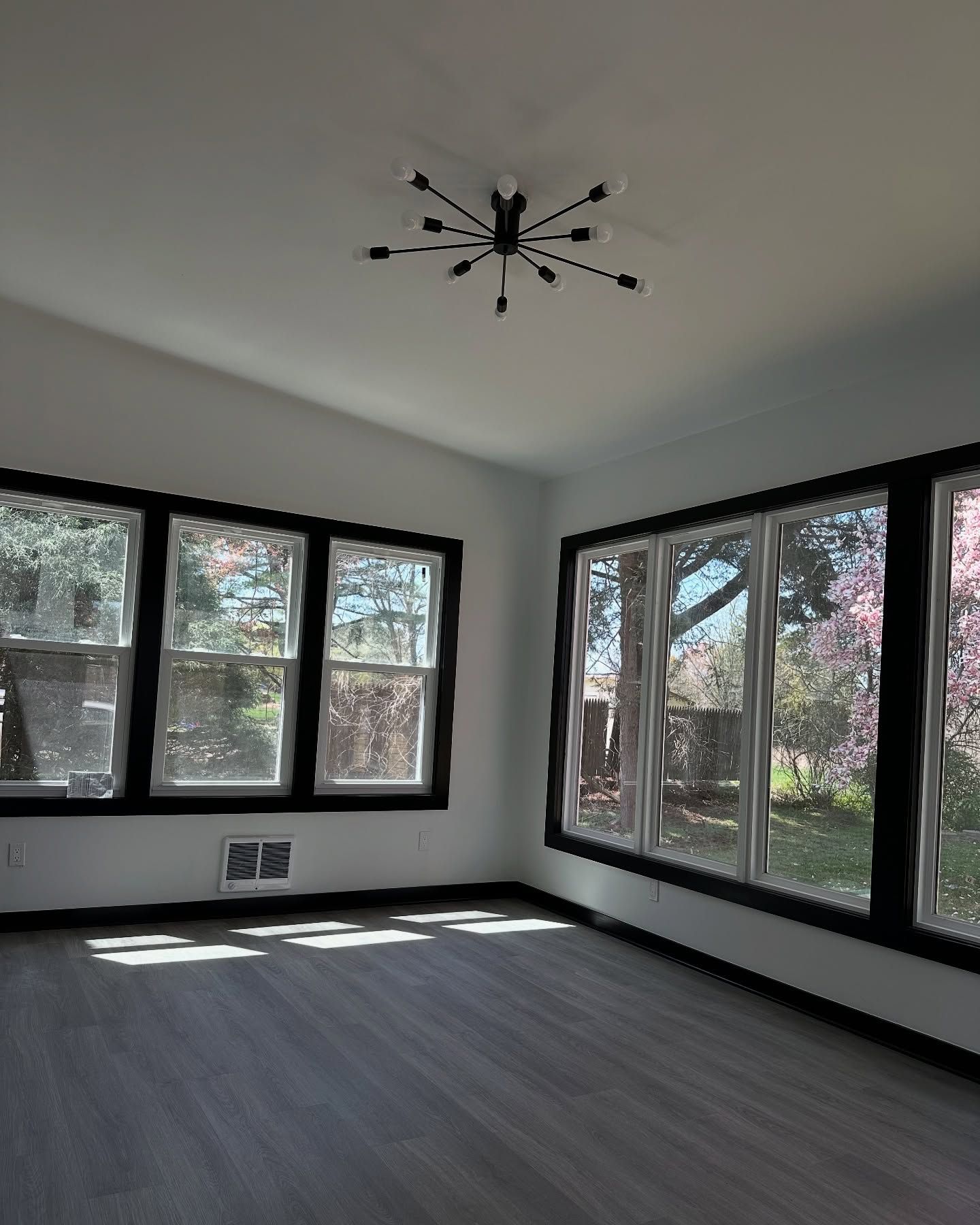 An empty living room with lots of windows and a ceiling fan.