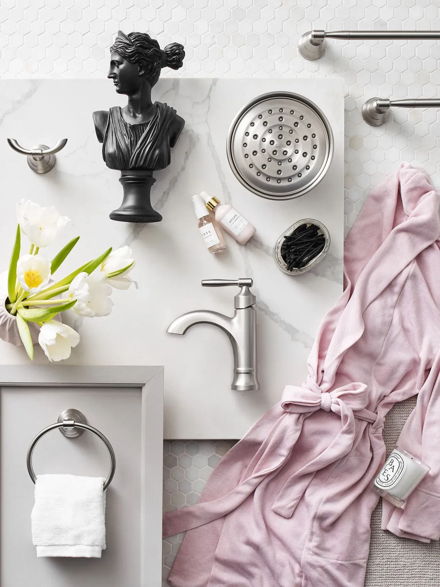 A bathroom with a bathrobe , faucet , shower head , towel holder , and flowers.