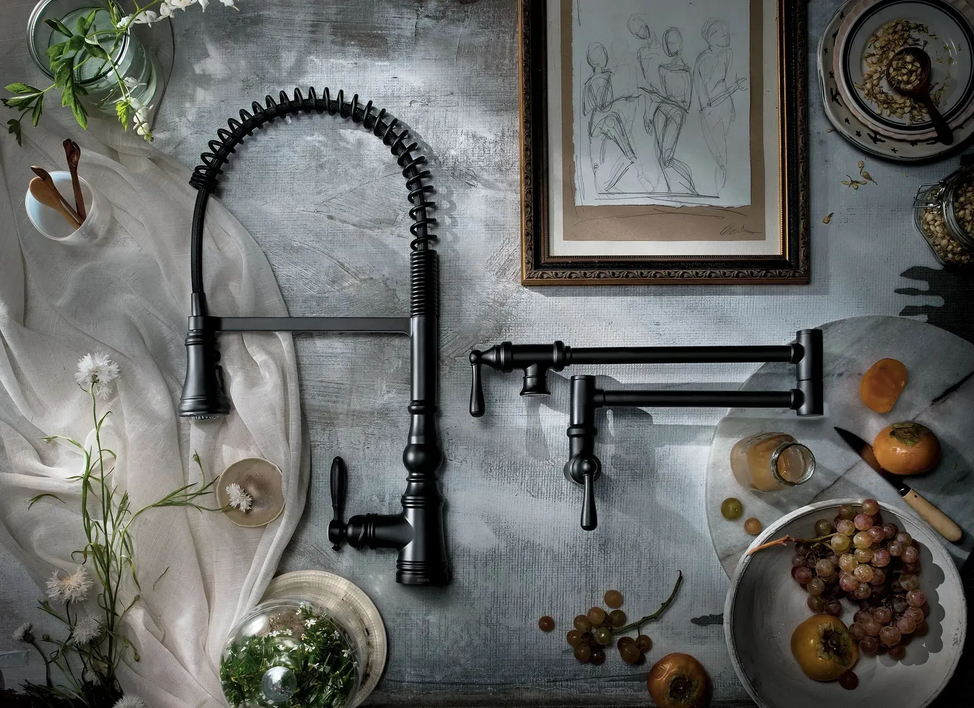 A kitchen sink faucet is sitting on top of a table with fruit and flowers.