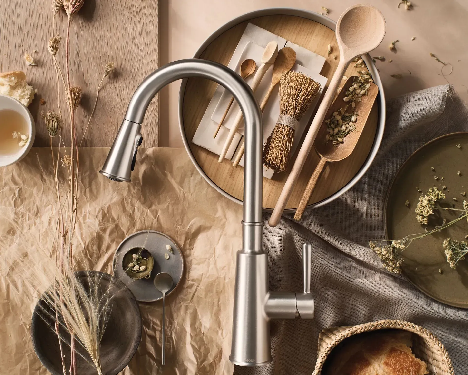 A stainless steel kitchen faucet is sitting on a table surrounded by food and utensils.