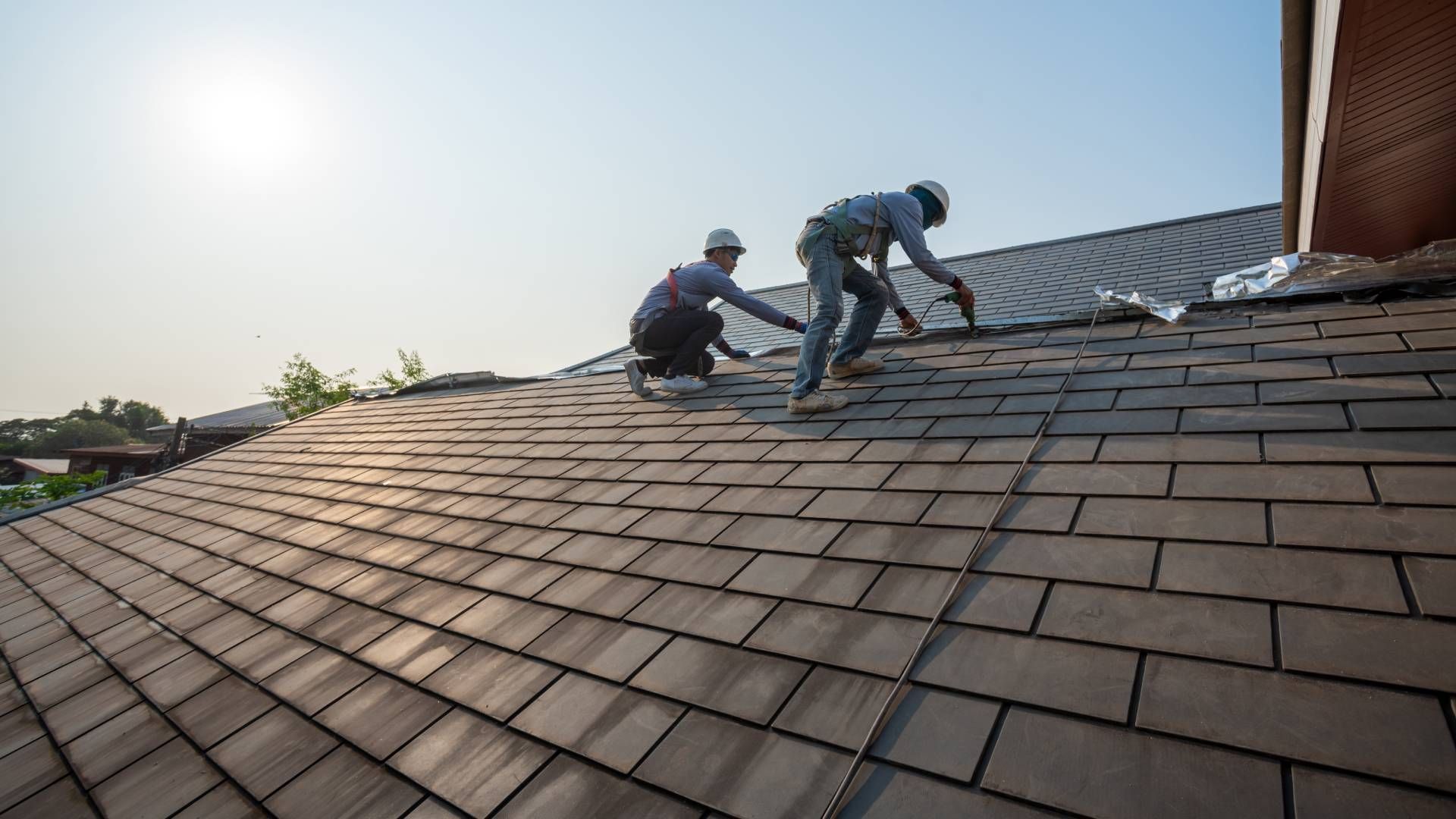 Two men are working on the roof of a house.