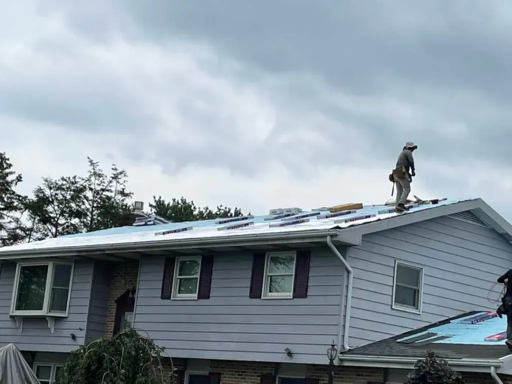 A man is standing on the roof of a house.
