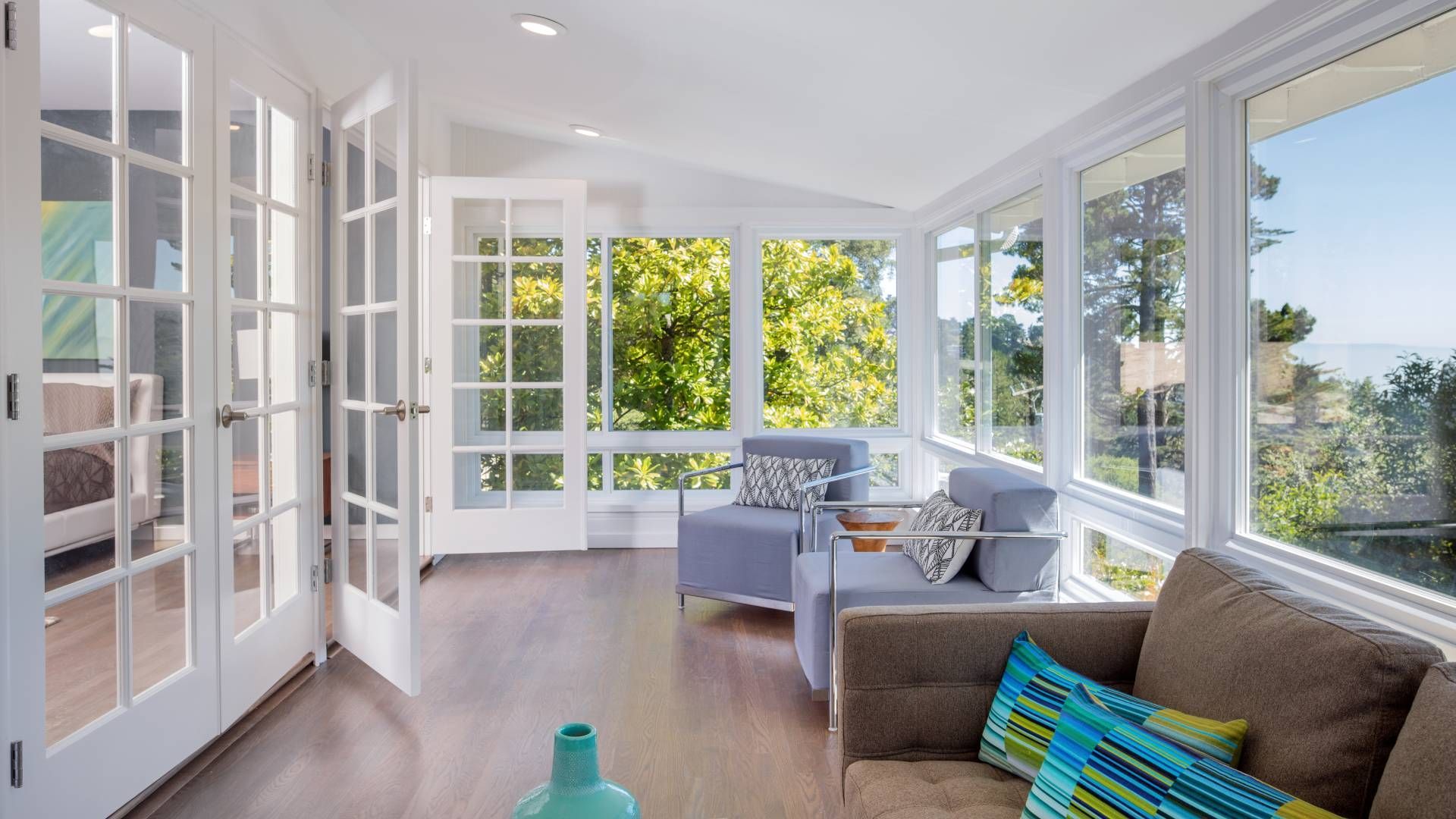 A living room with a couch , chairs , and lots of windows.