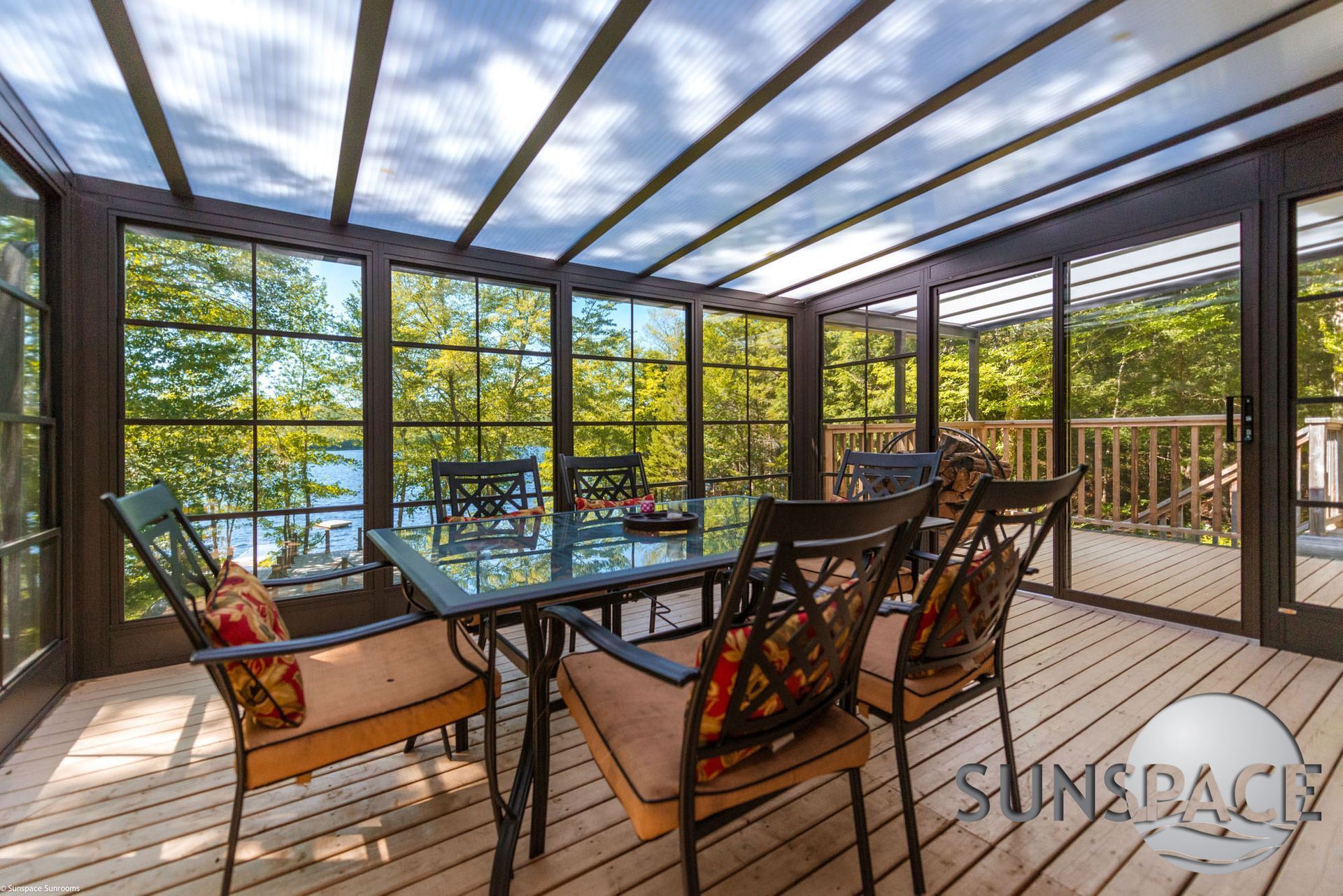 A sunroom with a table and chairs and a view of a lake.