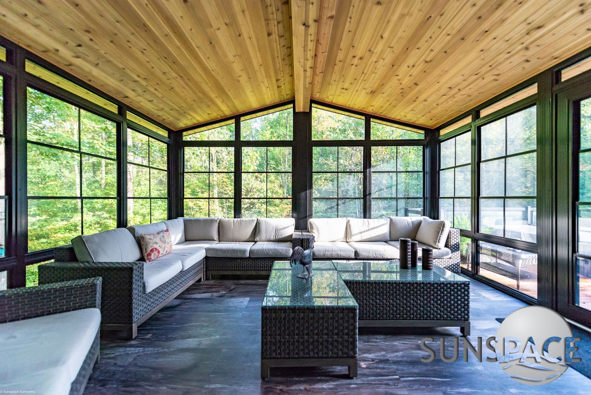A sunroom with a lot of windows and furniture.