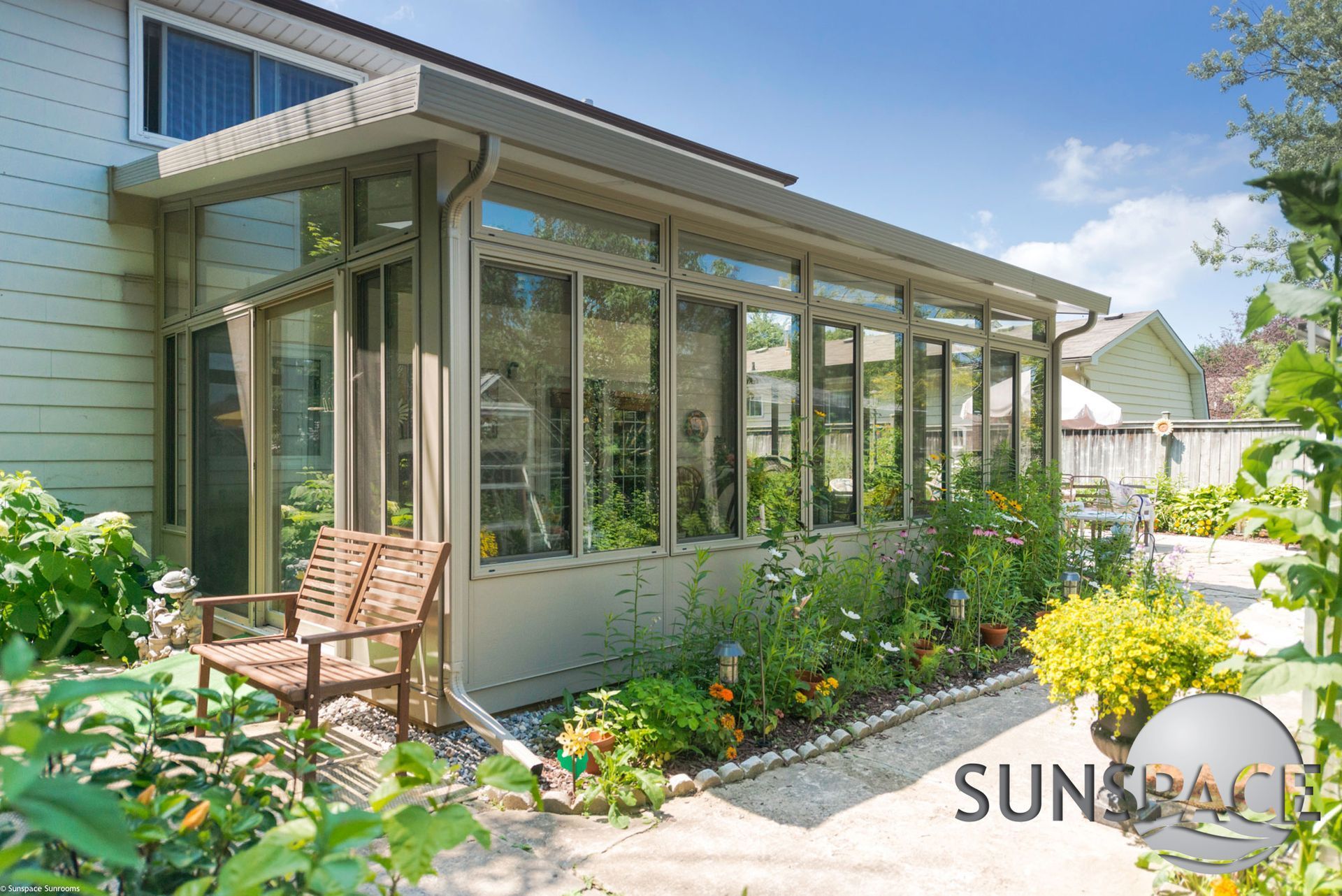 A sunroom with a bench and chairs in front of a house.