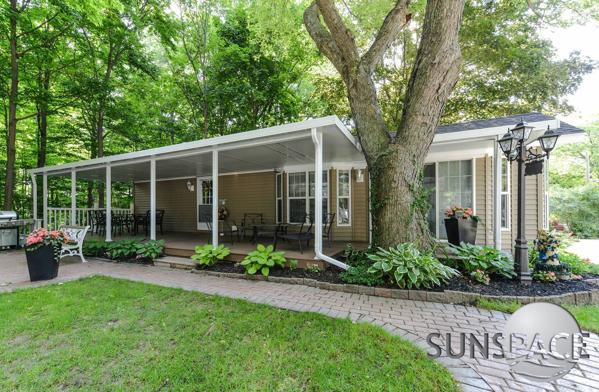 A house with a large porch and a tree in front of it.