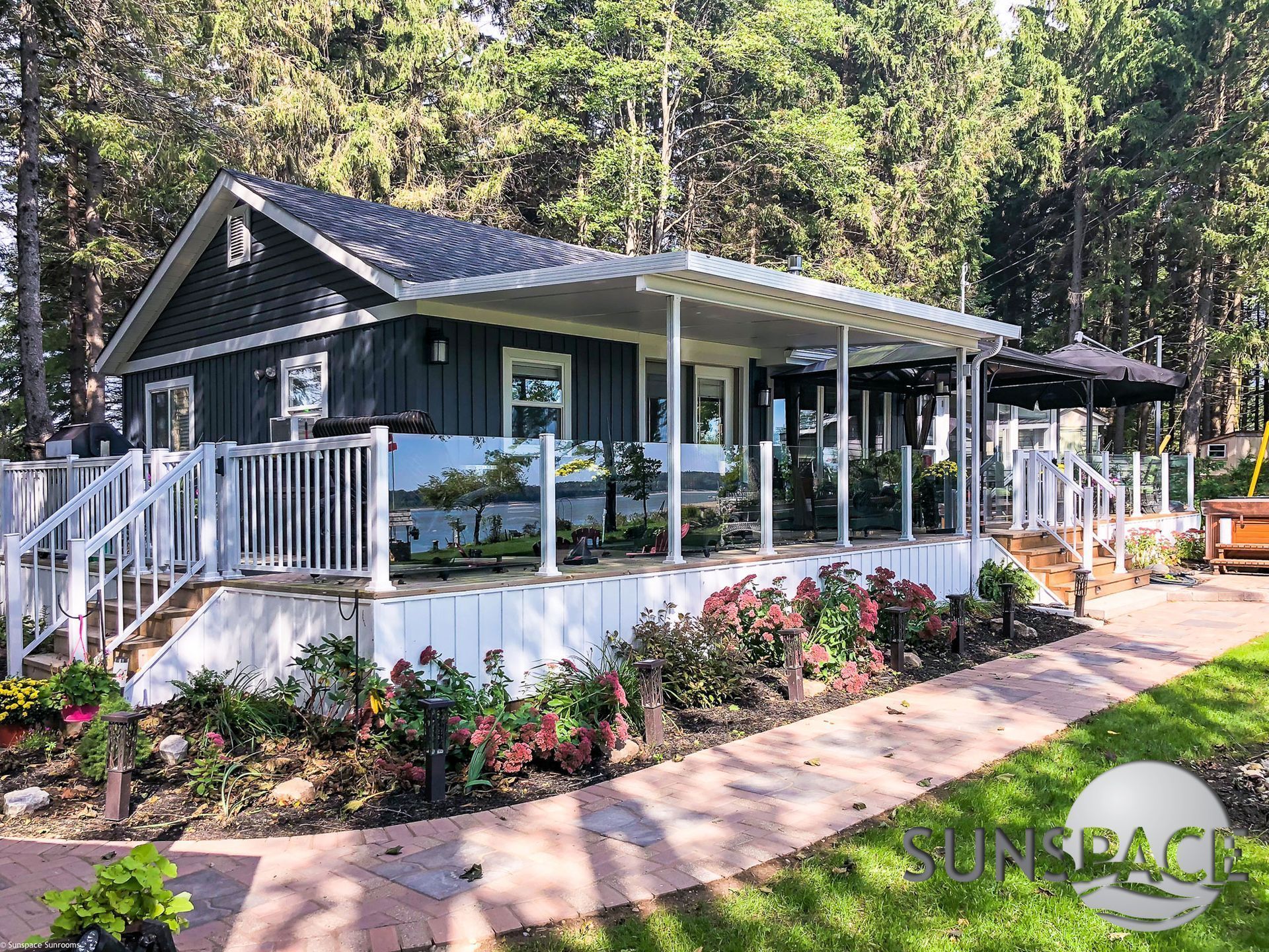 A small house with a porch and stairs is surrounded by trees.