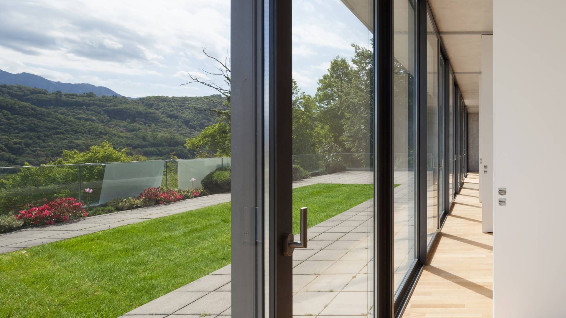 A large window with a view of a lush green field and mountains.