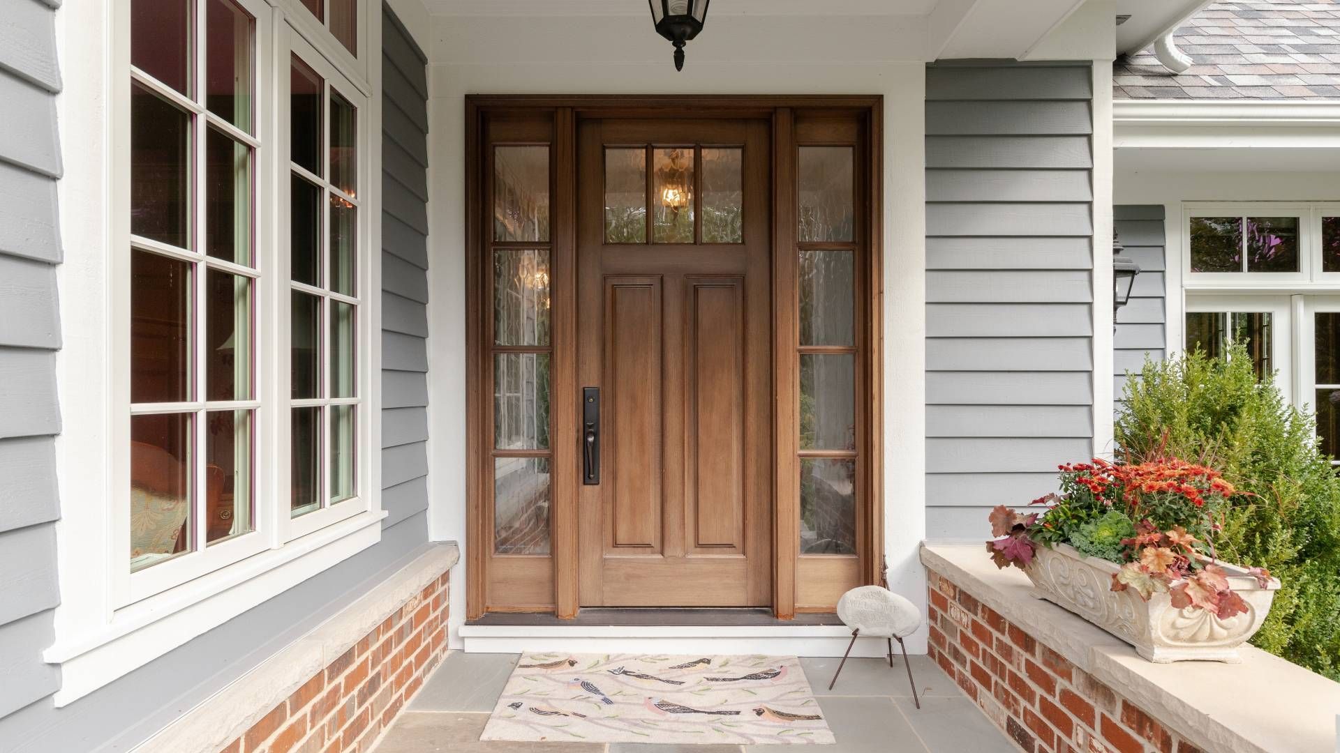 The front door of a house with a wooden door and a brick porch.