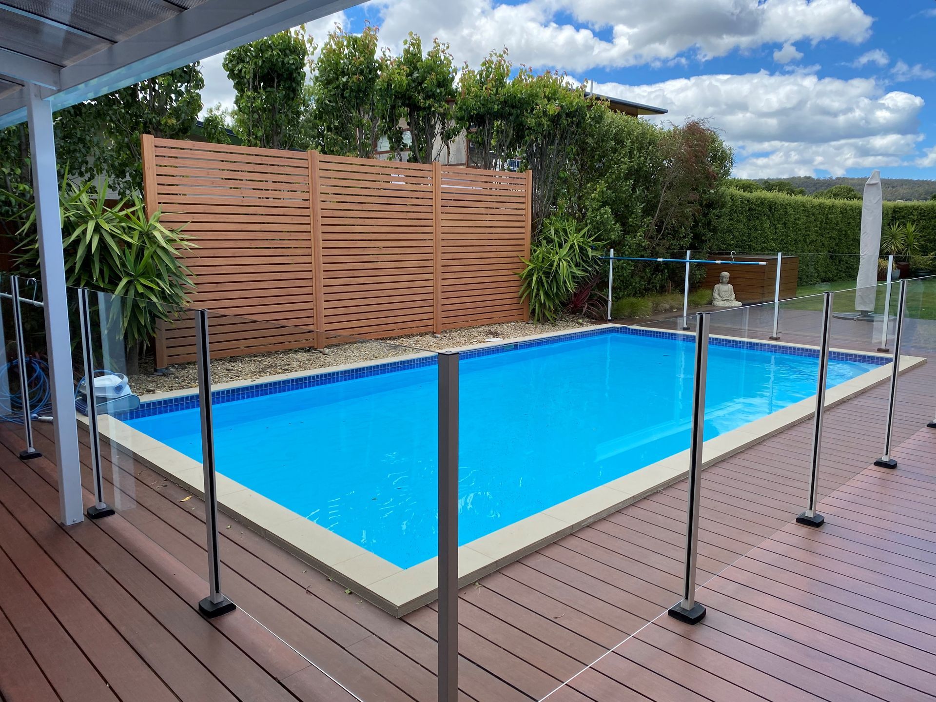 A large swimming pool is surrounded by a wooden deck and fence.