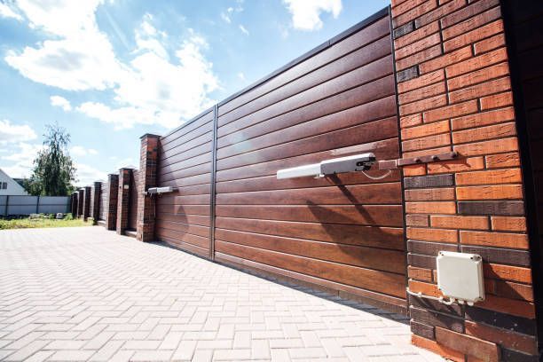 A wooden fence with a brick wall and a sliding gate.