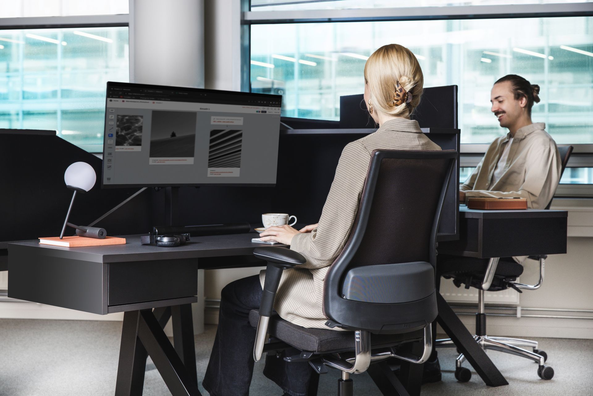 A woman is sitting at a desk in front of a computer.