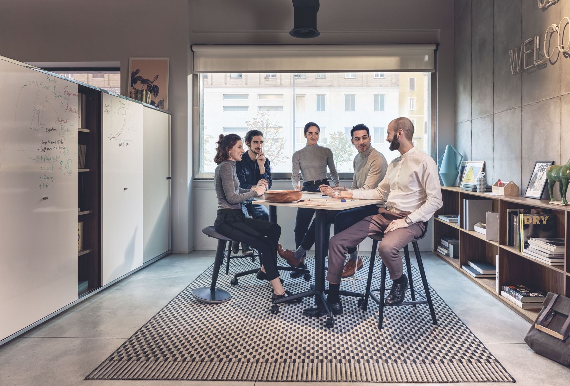 A group of people are sitting around a table in a room having a meeting.