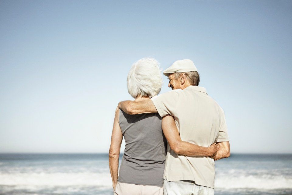 due anziani che si abbracciano in spiaggia