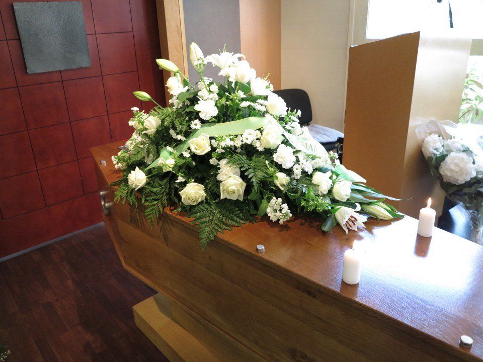 cassa funebre in legno con composizione floreale