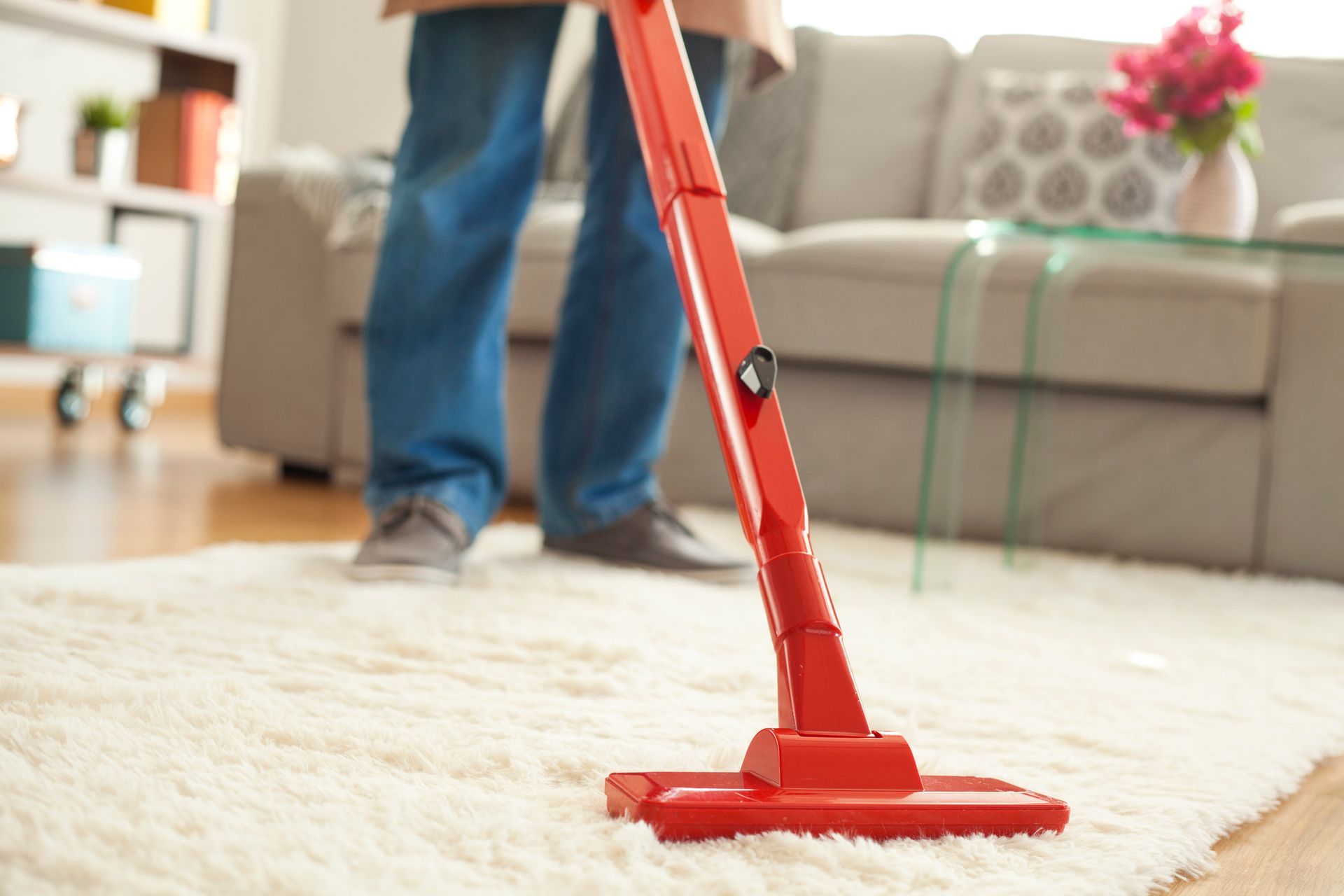 A man using a vacuum cleaner for carpet cleaning in a residential living room setting A man using a vacuum cleaner for carpet cleaning in a residential living room setting