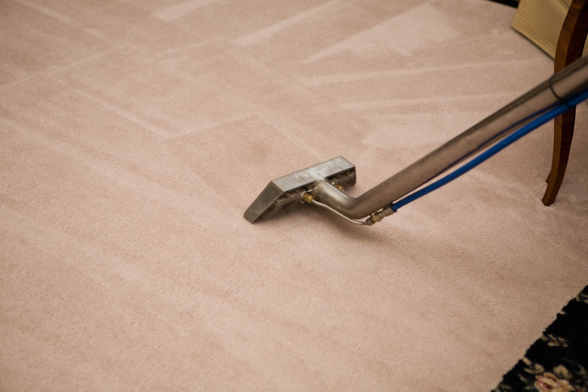 A vacuum cleaner is being used to clean a carpet in a living room.