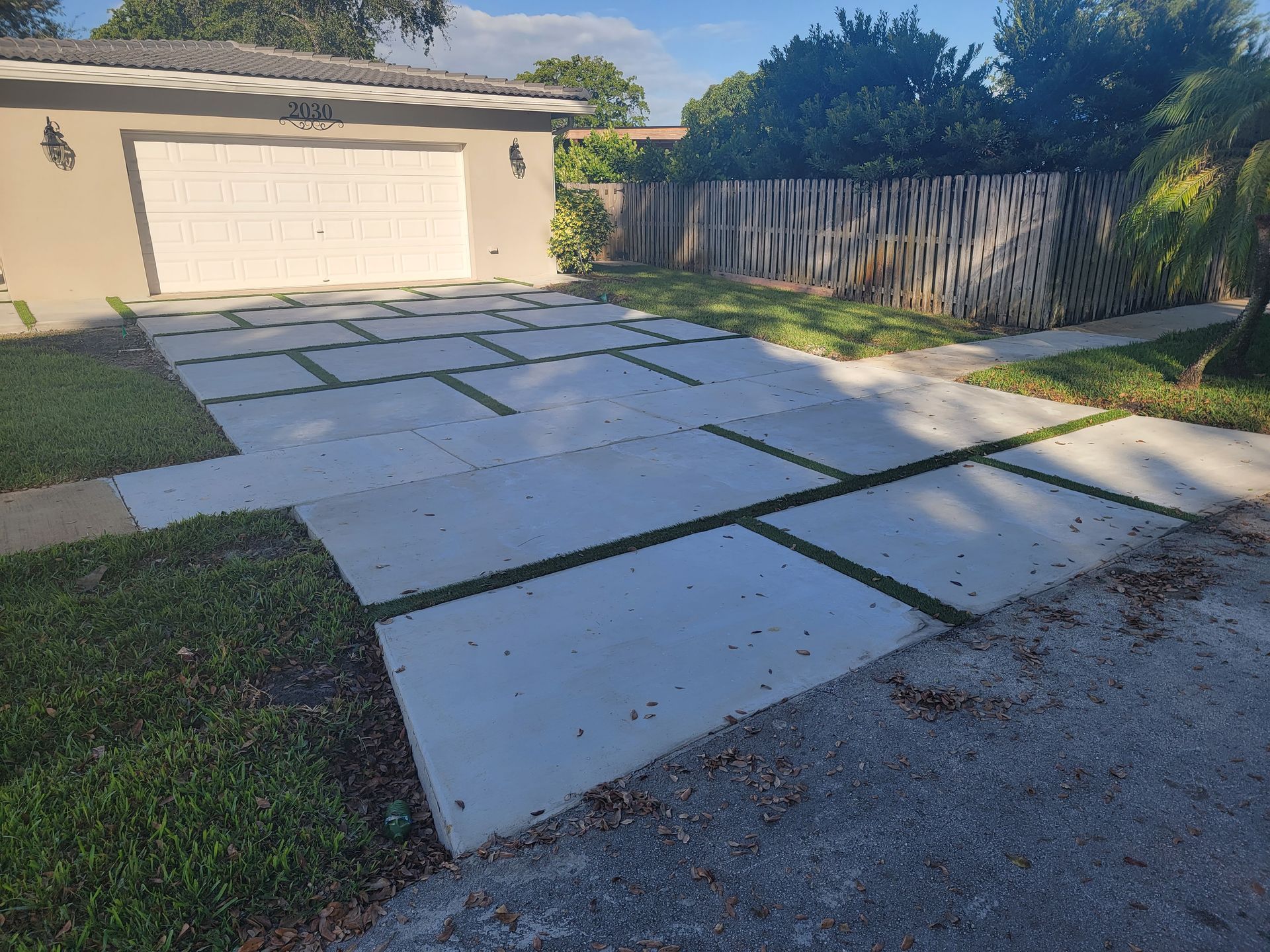 A driveway in front of a house with a garage and a fence.