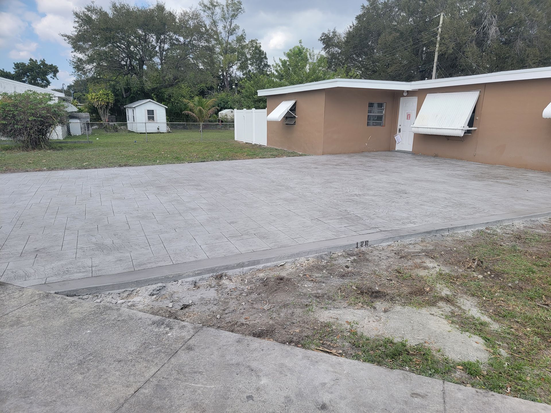 A house with a driveway and awnings on the windows.