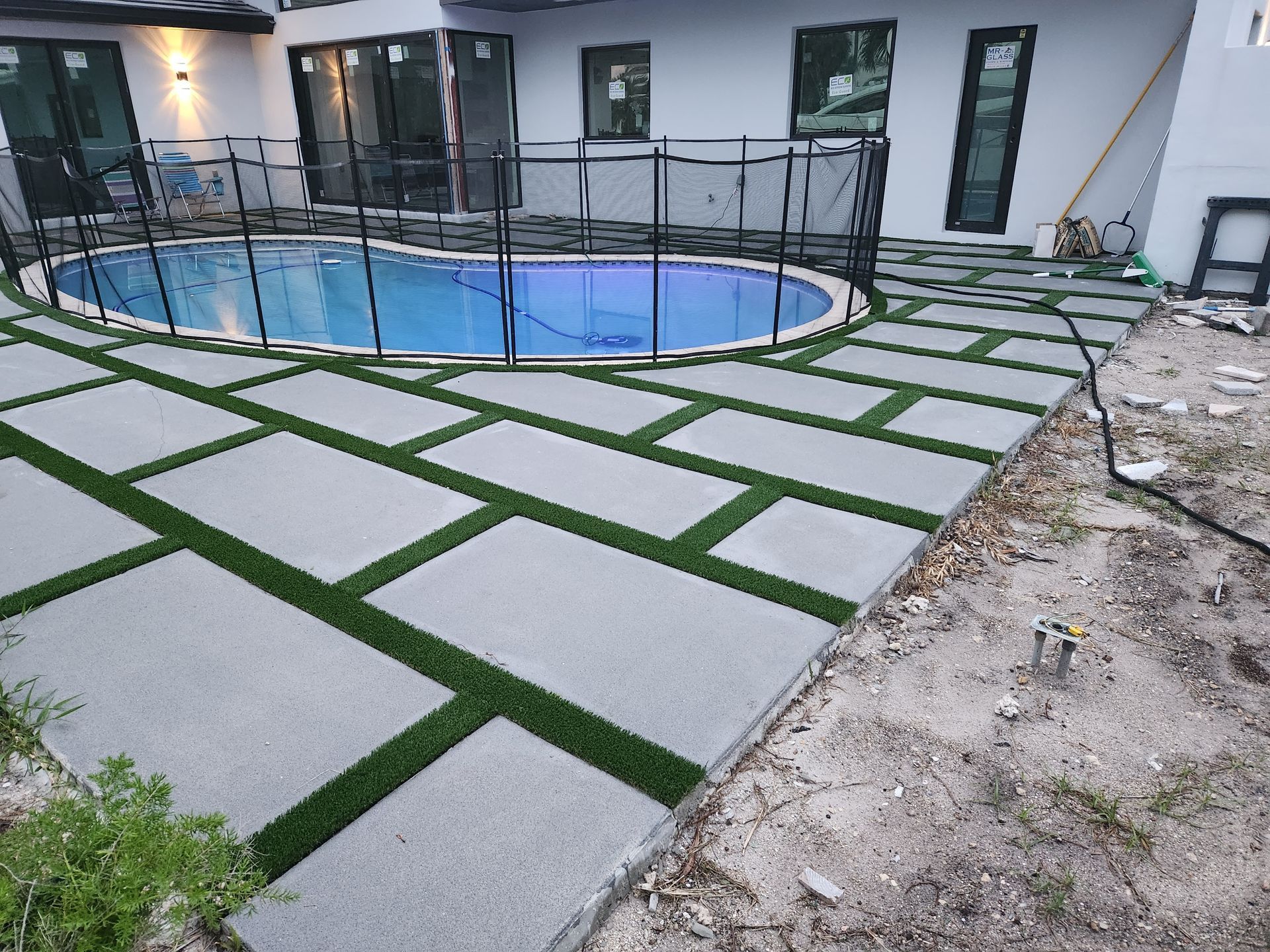 A swimming pool is surrounded by a fence and a patio.