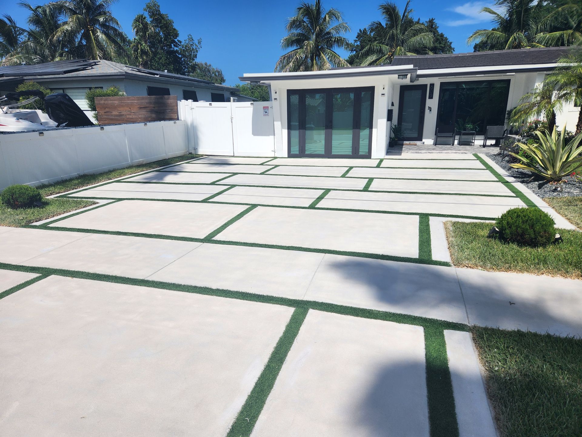 A Concrete Driveway with Green Lines Leading to A House