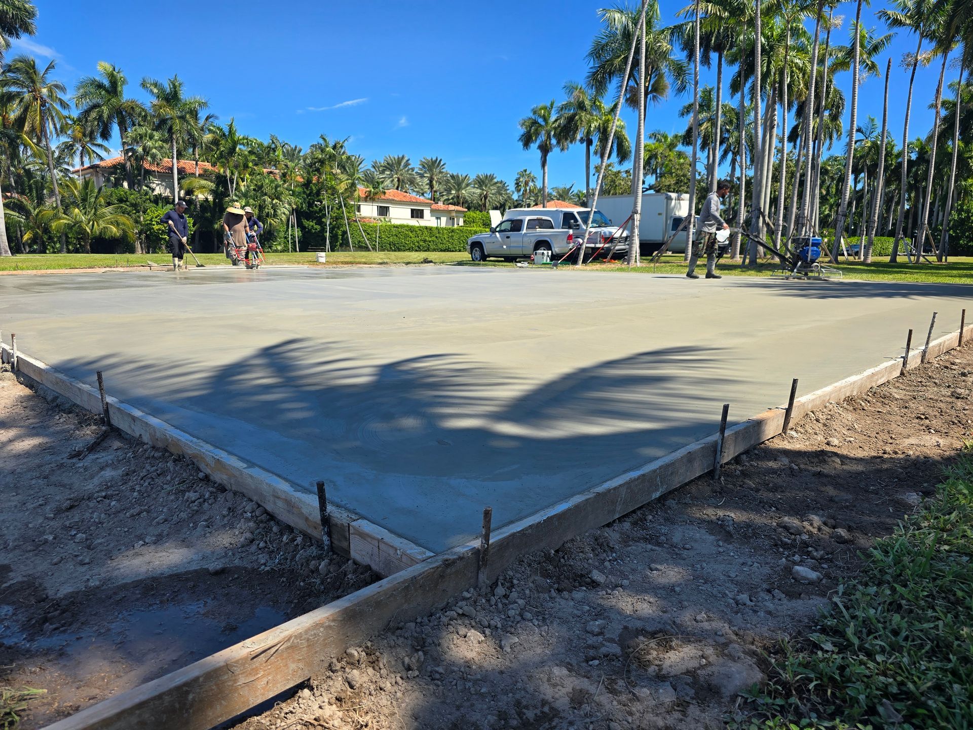 A Concrete Driveway Is Being Built in A Parking Lot with Palm Trees in The Background.