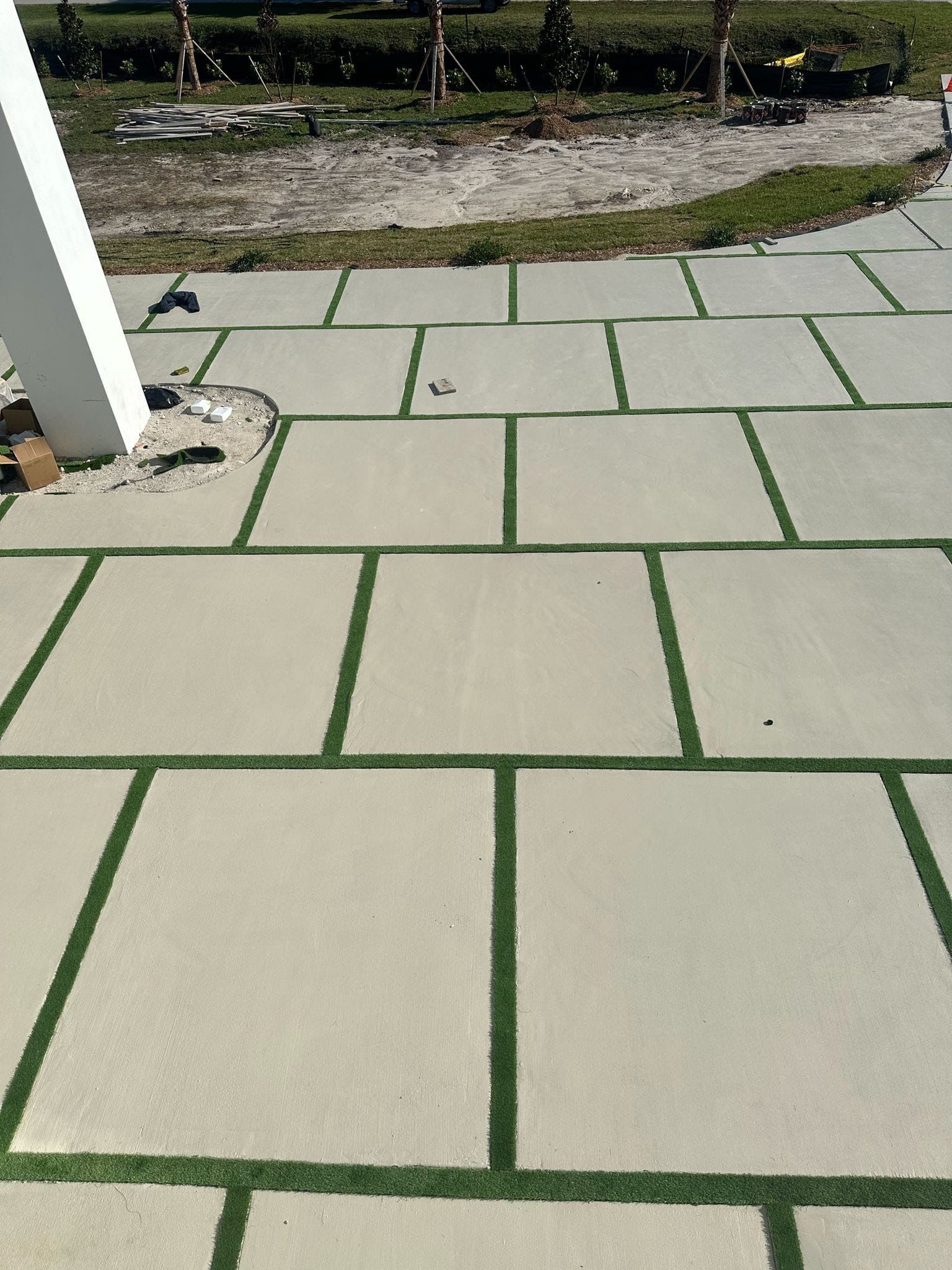 A concrete driveway with green lines on it and a white pole in the background.