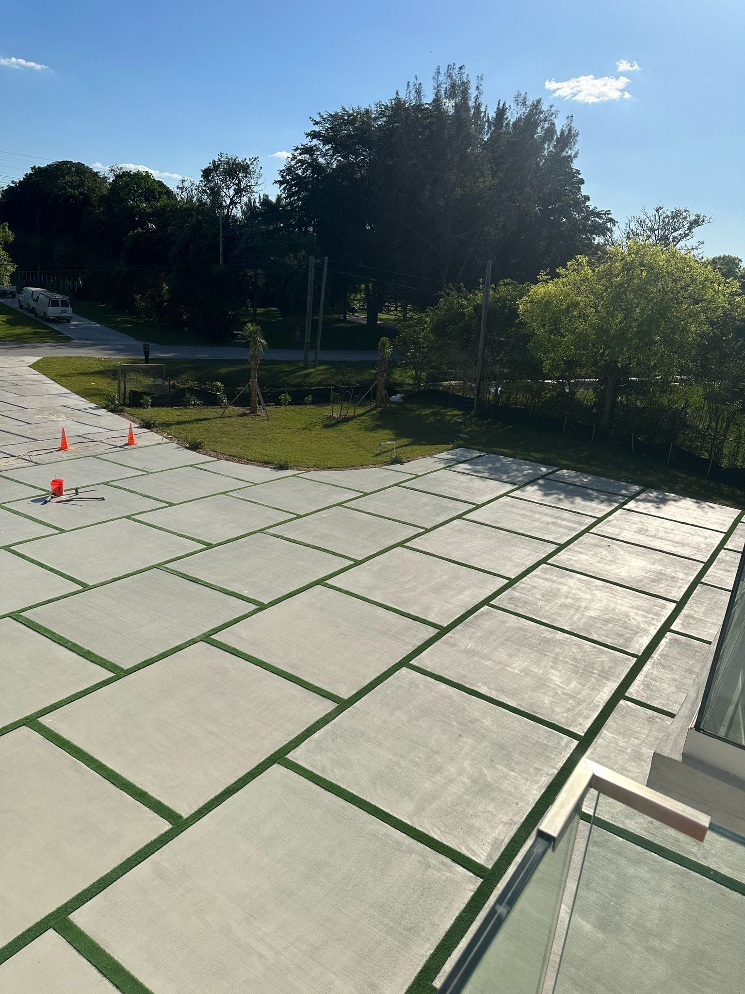 A concrete driveway with green lines and trees in the background