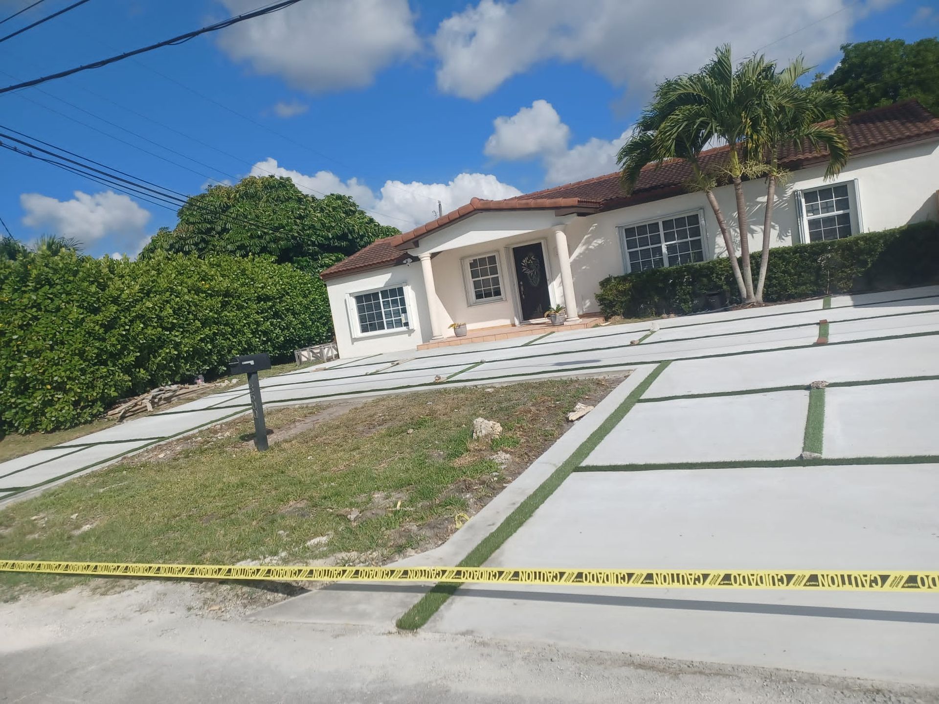 A house with a concrete driveway is surrounded by yellow tape