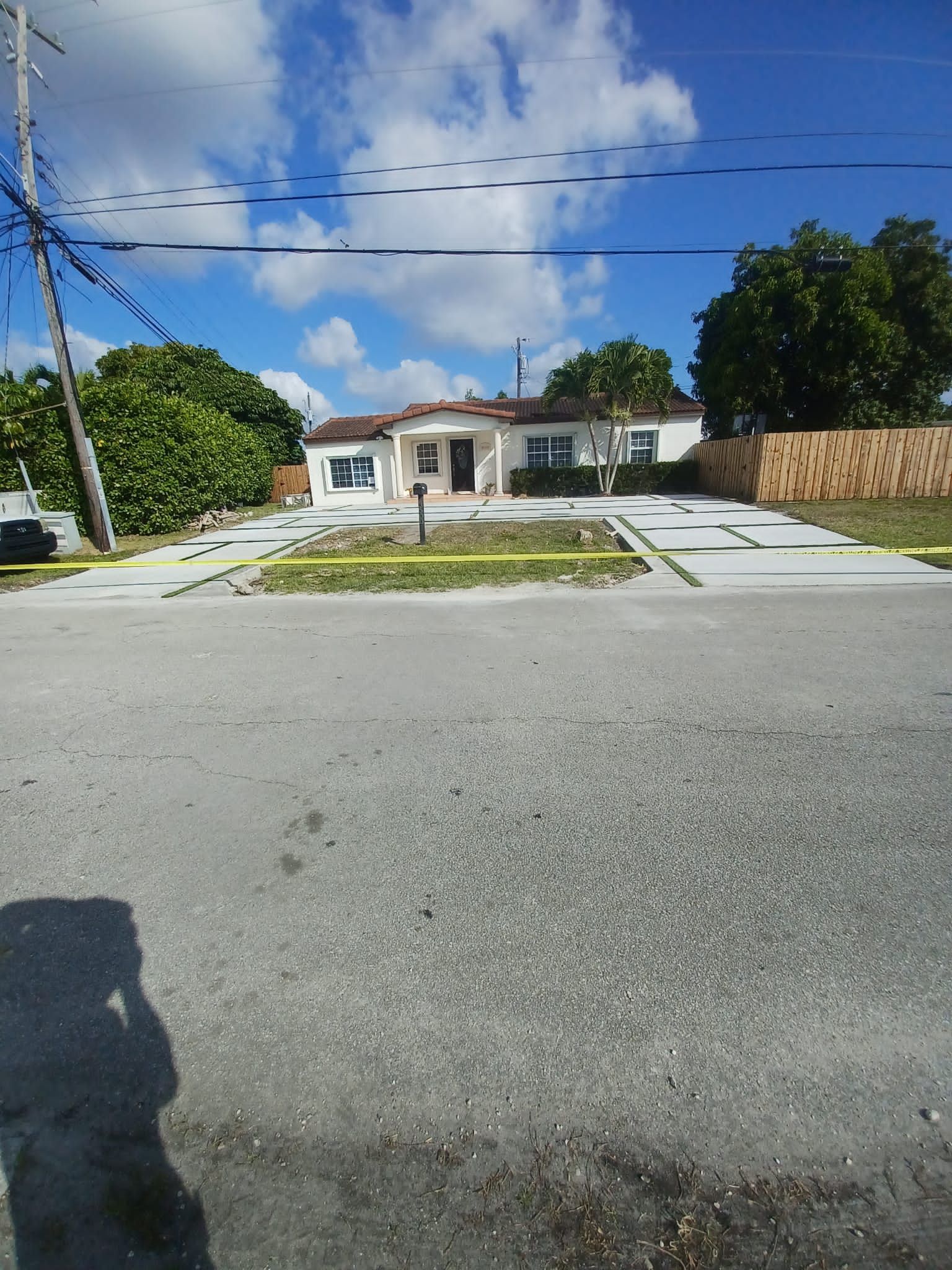 A shadow of a person is cast on the road in front of a house