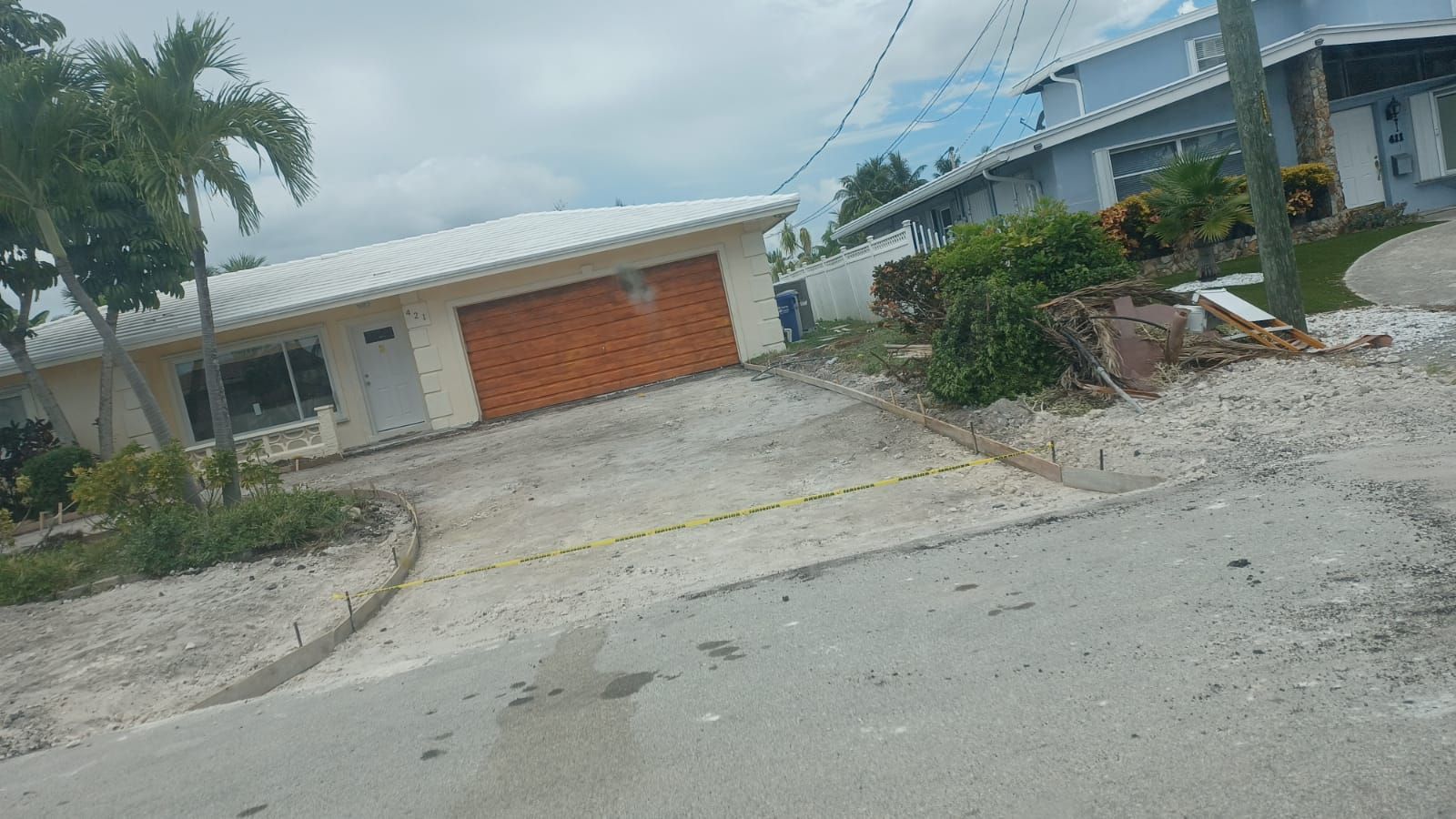 A house with a garage is sitting on the side of the road.